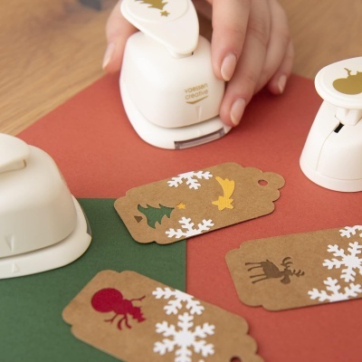 Carimbos brancos festivos e etiquetas de papel kraft decoradas com motivos natalícios em mesa