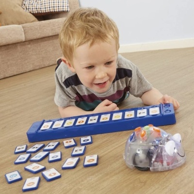 Criança brinca com brinquedo educativo azul com cartas e robô transparente no chão de madeira