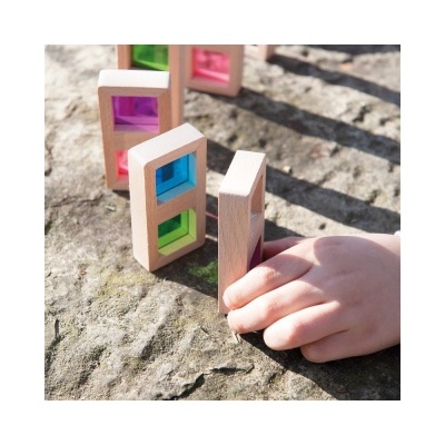 Peças de madeira com vidro colorido e mão infantil sobre pedra