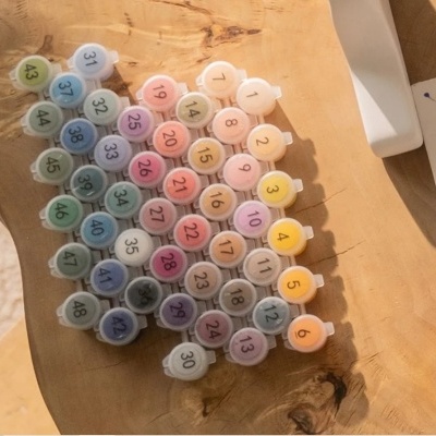 Conjunto de potes de tinta colorida numerados de 1 a 48 sobre madeira