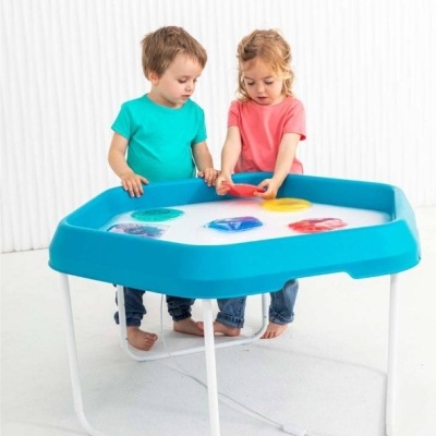 Mesa de atividades azul com crianças interagindo