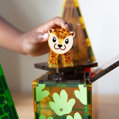 Figura de leopardo de plástico transparente âmbar sobre blocos de construção verdes com folhas