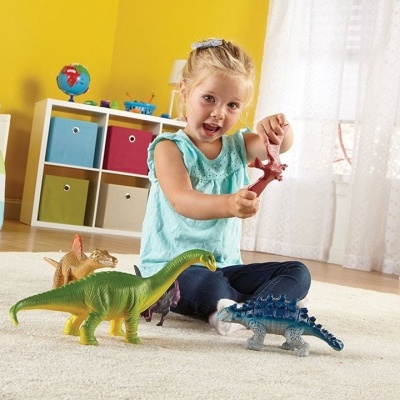 Criança brinca com dinossauros de brinquedo em quarto colorido com parede amarela