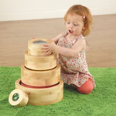 Criança a brincar com blocos redondos de madeira numa sala