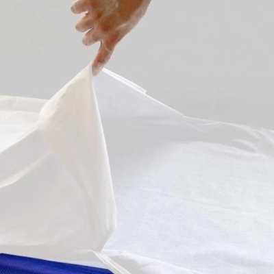 Lençol branco a ser colocado em colchão azul