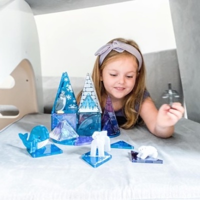 Menina a brincar com peças de acrílico azul translúcido em formas de animais e edifícios
