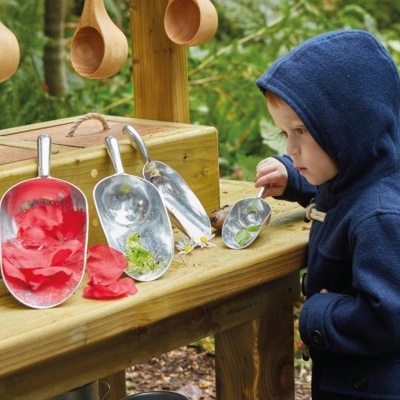 Quatro pás metálicas e uma criança em capuz azul em jardim com estrutura de madeira