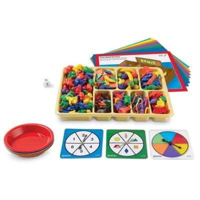 Conjunto educativo com peças coloridas, dados, discos de jogo, pratos vermelhos e cartões num suporte de plástico.