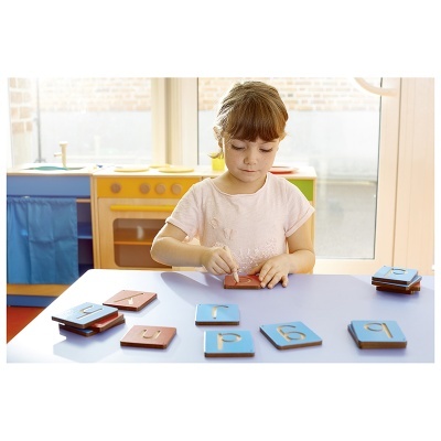 Criança a jogar com peças de madeira com letras e números.