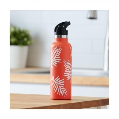 Garrafa laranja com folhas brancas e tampa preta numa mesa de madeira