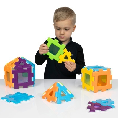 Criança brinca com blocos de construção coloridos em formas geométricas