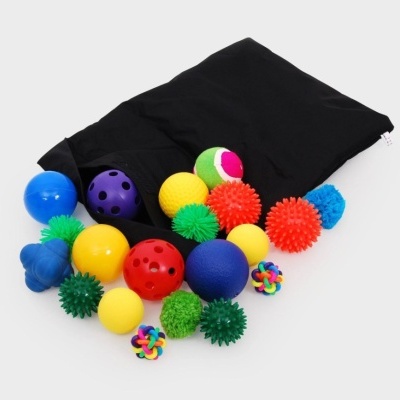Conjunto de bolas e objetos sensoriais coloridos em vários tamanhos e texturas com saco preto