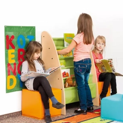 Crianças a ler livros com mobiliário colorido e painel de tecido com letras na parede