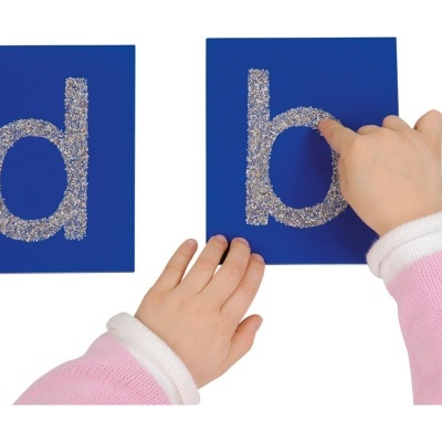 Cartas azuis com letras texturizadas e mãos de criança vestindo rosa e branco