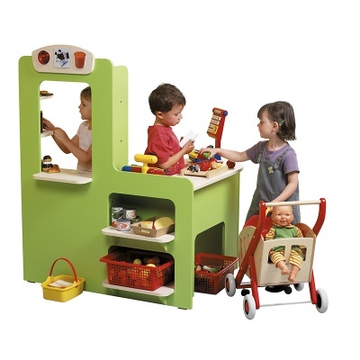 Crianças a brincar com brinquedo de supermercado infantil em madeira verde e vermelho, com prateleiras, alimentos de plástico, caixa registadora e carrinho com boneca.