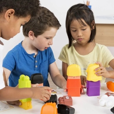Crianças brincando com bonecos de plástico coloridos numa mesa branca indoors