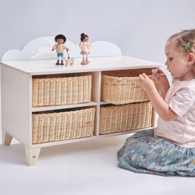 Móvel com cestos de vime e decoração de nuvens, menina a brincar ao lado