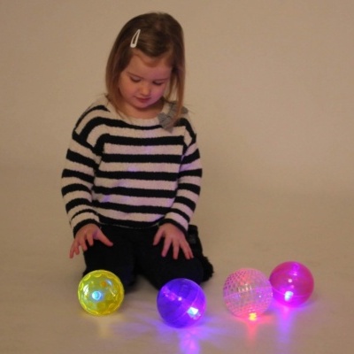 Criança com bolas luminosas coloridas no chão