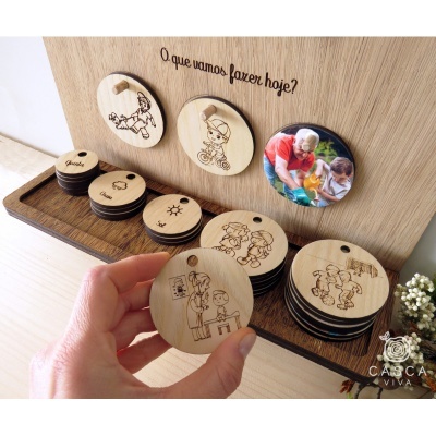 Painel de madeira com discos de madeira gravados com desenhos de crianças e texto em português