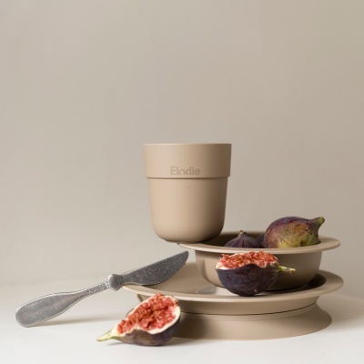 Conjunto de utensílios creme para criança com figos frescos e faca de plástico prata em fundo neutro