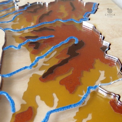 Objeto decorativo em acrílico com padrões amarelos, castanhos e azuis sobre madeira clara