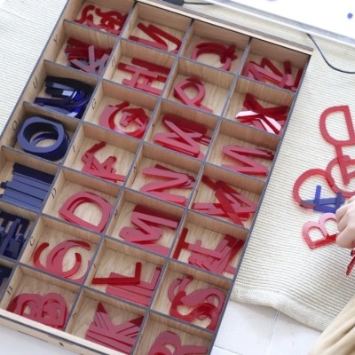 Letras coloridas em caixa de madeira com criança a mexer nas letras