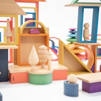 Brinquedos de madeira coloridos com formas geométricas e figuras em superfície branca.