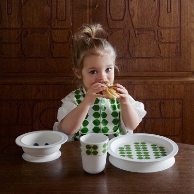 Conjunto de louça infantil branca com padrão verde em mesa de madeira
