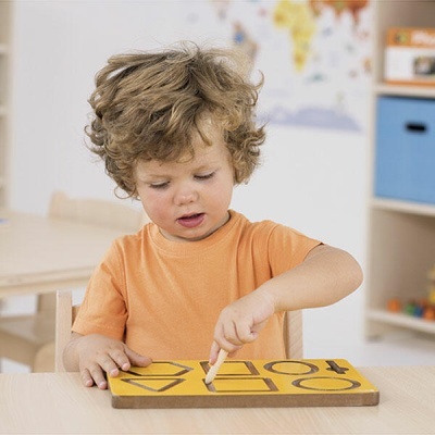 Criança com t-shirt laranja a usar tabuleiro de madeira com letras