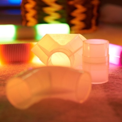 Peças plásticas translúcidas para tubos com luzes coloridas ao fundo.