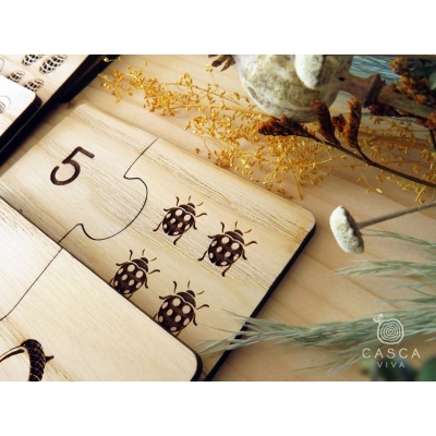 Peças de puzzle de madeira com número 5 e joaninhas, texto CASCA VIVA