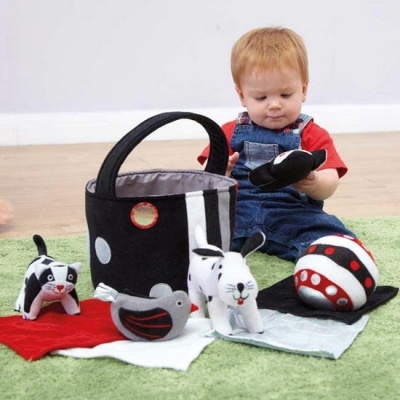 Menino a brincar com brinquedos macios em preto, branco e vermelho