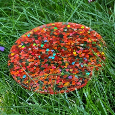 Disco redondo transparente com corações coloridos sobre relva