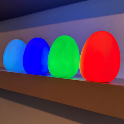 Quatro lâmpadas coloridas azul claro, azul escuro, verde e vermelho numa prateleira branca