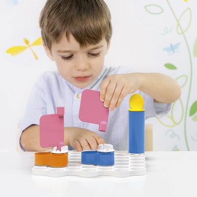 Menino a brincar com brinquedo educativo colorido em base branca numa sala clara