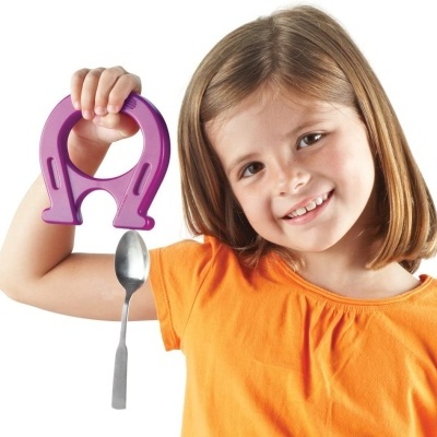 Menina com camisola laranja segura um íman roxo e uma colher metálica