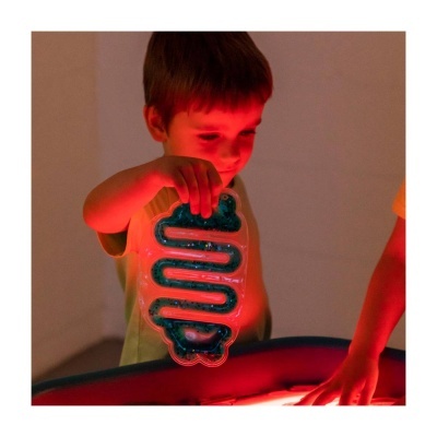 Criança a segurar objecto transparente com líquido azul iluminado com luz vermelha