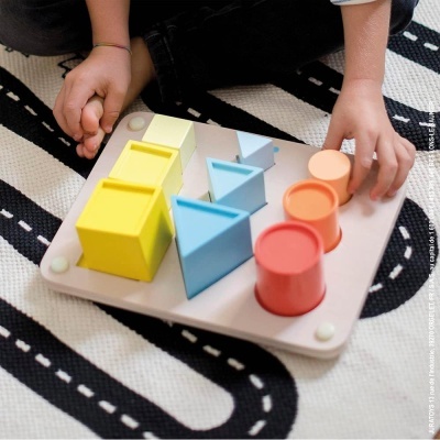 Tabuleiro de madeira com peças coloridas geométricas em tapete com padrão de estrada