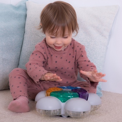 Criança brincando com brinquedo colorido sentada em tapete com almofadas
