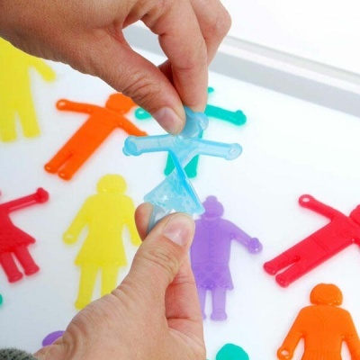 Figuras humanas coloridas de plástico numa superfície branca, mãos segurando uma figura azul