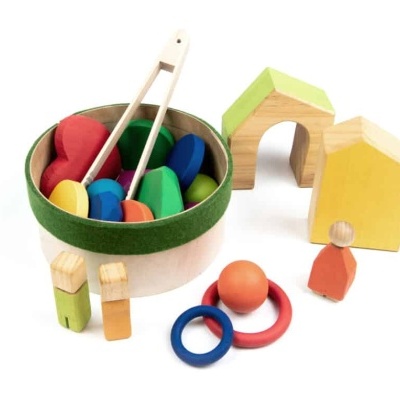 Brinquedos de madeira coloridos com peças redondas, casas e figuras humanas