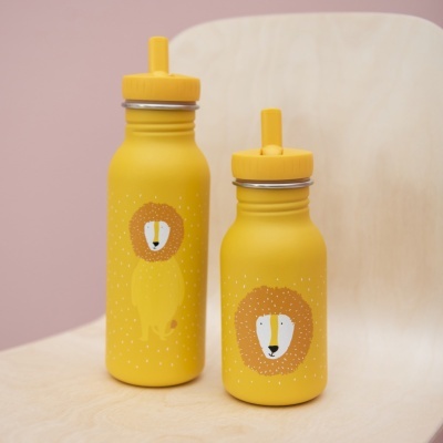 Duas garrafas amarelas com estampa de leão sobre cadeira de madeira clara