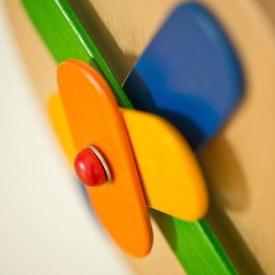 Peça decorativa de madeira colorida com botão vermelho central