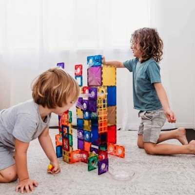 Crianças a brincar com blocos magnéticos coloridos em tapete cinzento
