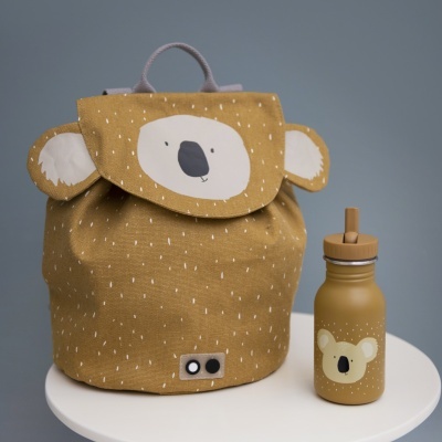 Mochila infantil amarela com estampa de urso e garrafa amarela com estampa de urso sobre mesa branca