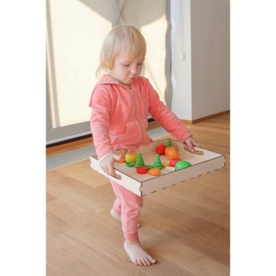 Criança com roupa cor-de-rosa a segurar caixa com brinquedos de madeira coloridos