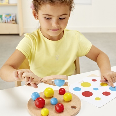 Menina a brincar com bolas de madeira coloridas e base com buracos