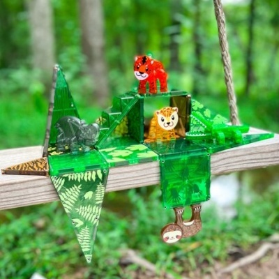 Brinquedo pendurado verde com figuras de animais coloridos numa corda, em ambiente natural