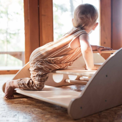 Criança a escalar brinquedo de madeira interior perto de janela