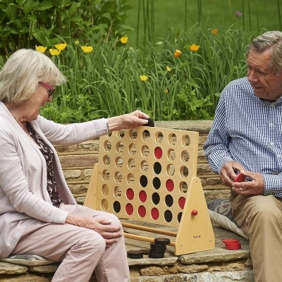 idosos jogando jogo de tabuleiro de madeira num banco de pedra num jardim